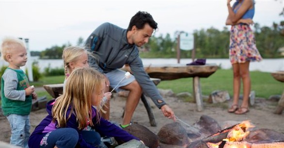 Family roasting marshmallows near a bonfire
